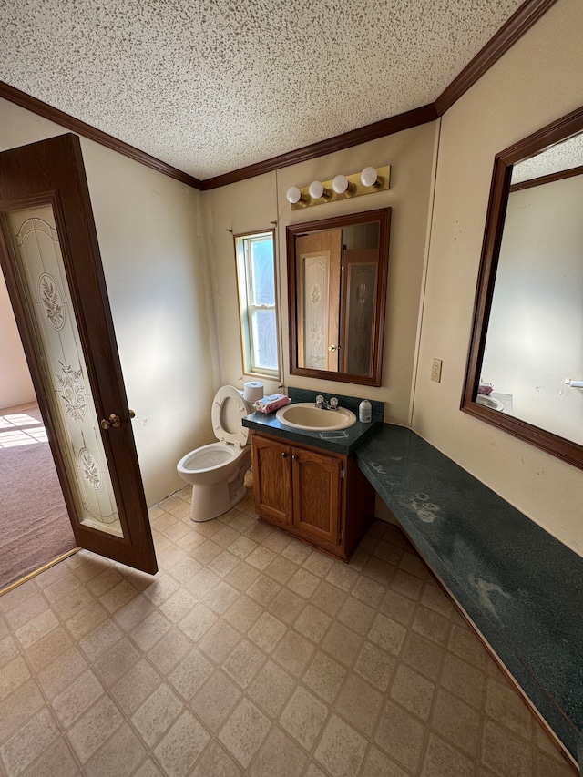 bathroom with a textured ceiling, toilet, vanity, tile patterned floors, and crown molding