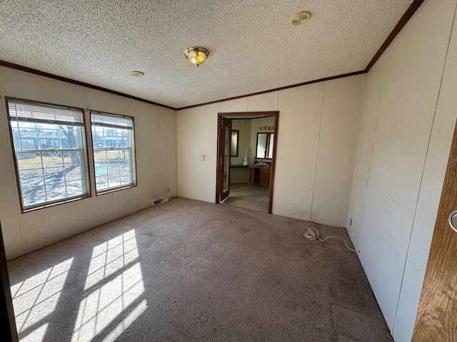 unfurnished room featuring visible vents, light colored carpet, ornamental molding, vaulted ceiling, and a textured ceiling