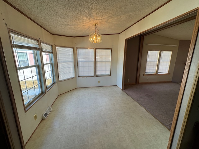 spare room featuring a textured ceiling, a notable chandelier, light carpet, visible vents, and ornamental molding