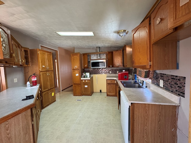 kitchen featuring light countertops, stainless steel microwave, and brown cabinetry