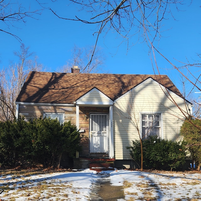 bungalow-style house with a shingled roof and a chimney