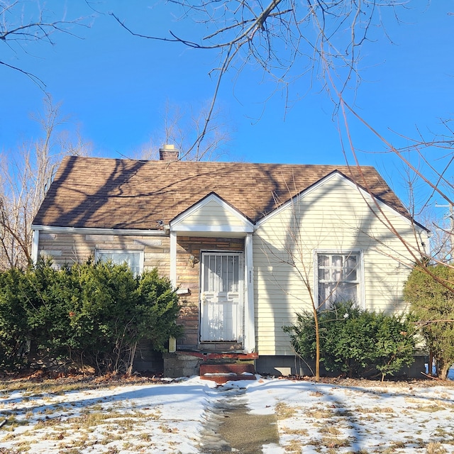 bungalow featuring a shingled roof and a chimney