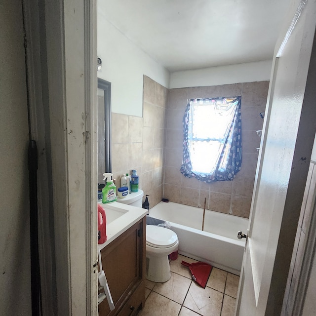 full bathroom featuring toilet, a bathing tub, tile patterned flooring, vanity, and tile walls