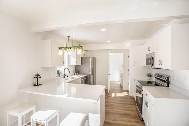 kitchen featuring appliances with stainless steel finishes, pendant lighting, light countertops, and a peninsula