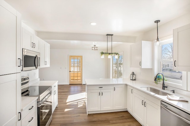 kitchen featuring stainless steel appliances, pendant lighting, light countertops, and a peninsula