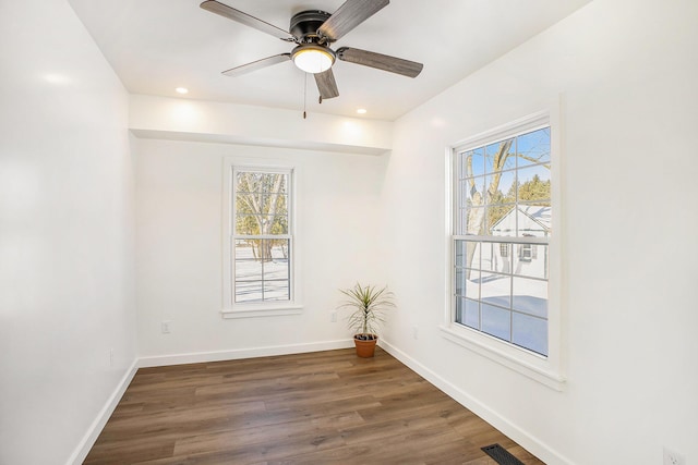 empty room with dark wood finished floors, a wealth of natural light, and baseboards