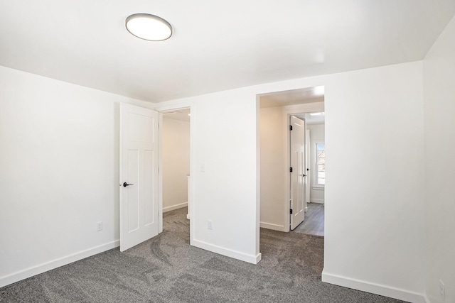 interior space with dark colored carpet and baseboards