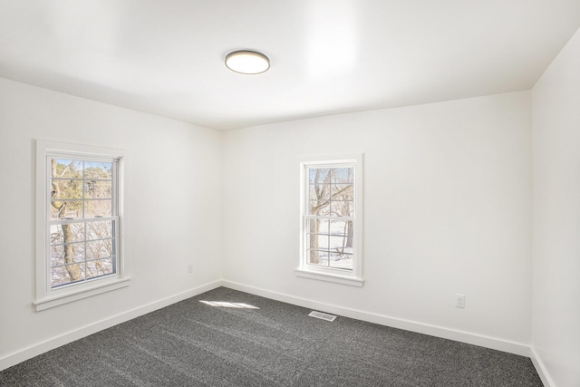 unfurnished room featuring a healthy amount of sunlight, carpet, visible vents, and baseboards