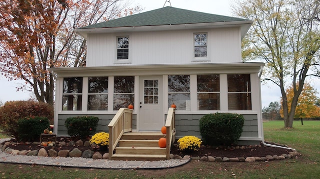 view of front facade with roof with shingles and a sunroom