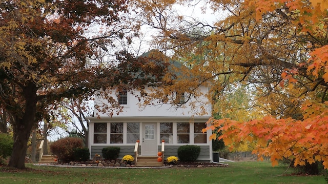 view of front of home featuring entry steps, a front yard, and a sunroom