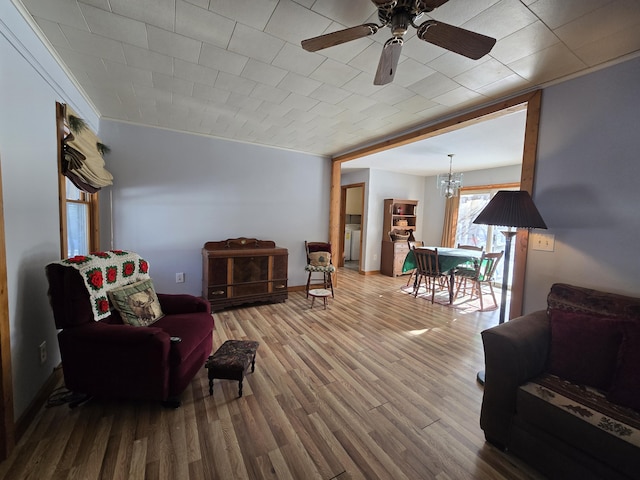 sitting room with ceiling fan with notable chandelier, wood finished floors, and baseboards