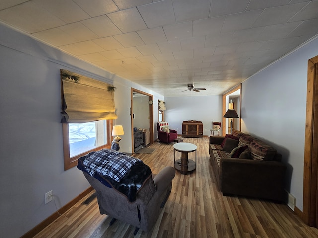 living area with a ceiling fan, baseboards, and wood finished floors