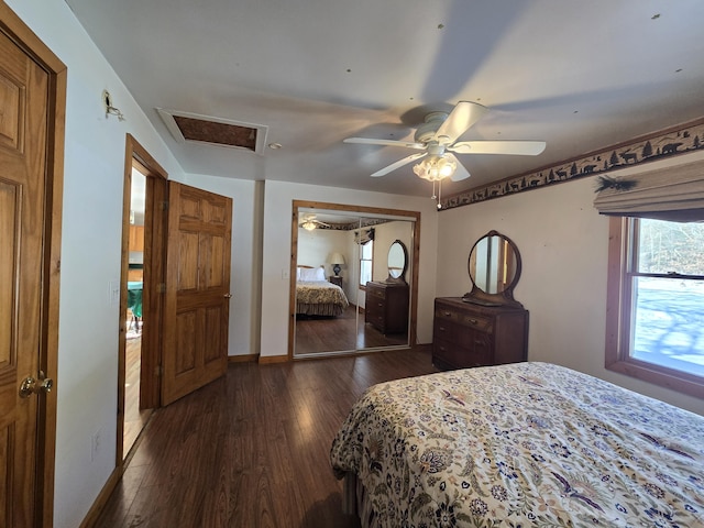 bedroom with dark wood-style flooring, a closet, attic access, ceiling fan, and baseboards