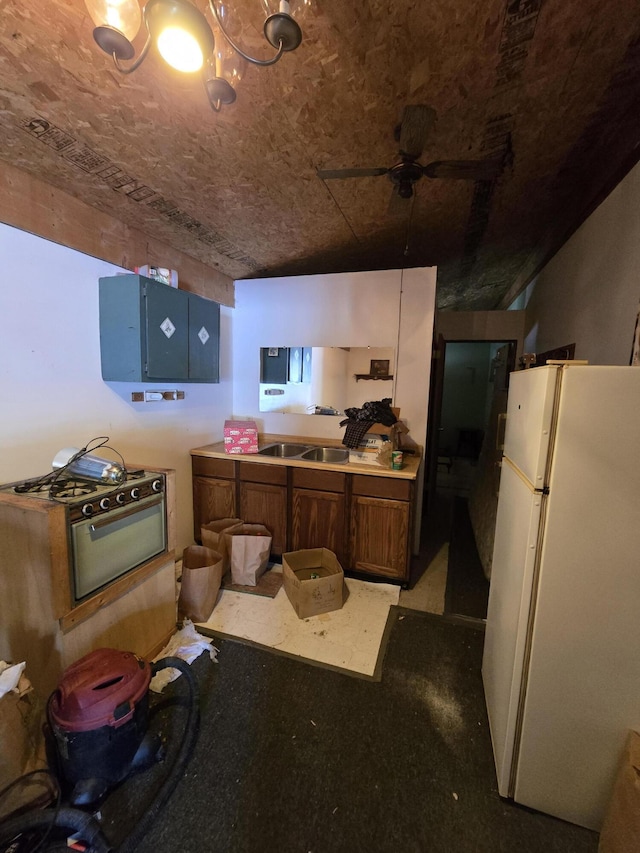 kitchen with freestanding refrigerator, ceiling fan, and a sink