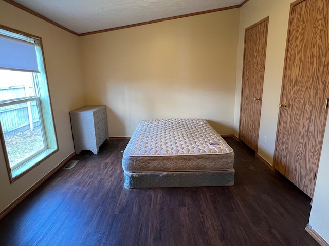 bedroom with dark wood-style floors, baseboards, visible vents, and crown molding