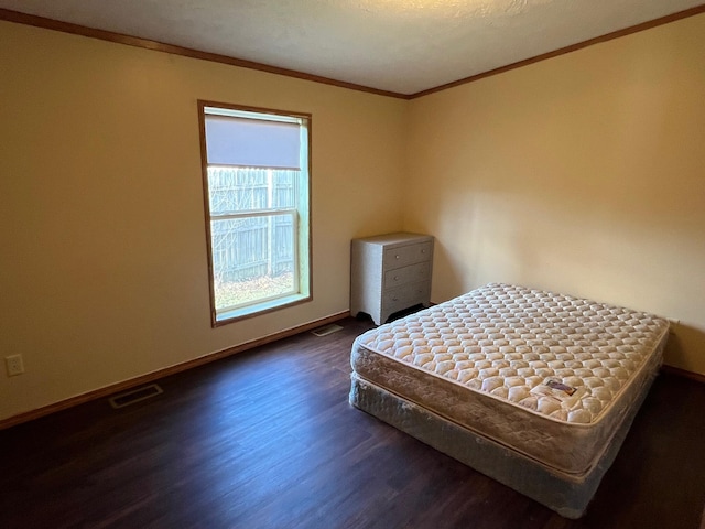 bedroom featuring ornamental molding, dark wood-type flooring, visible vents, and baseboards