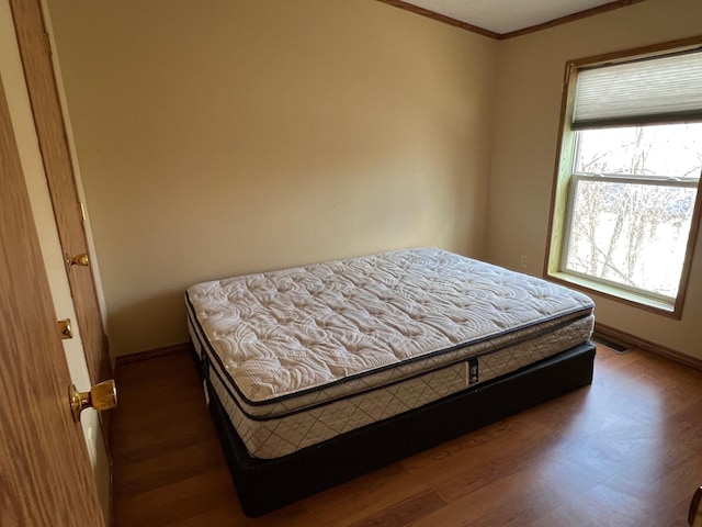 bedroom with dark wood-type flooring, visible vents, ornamental molding, and baseboards