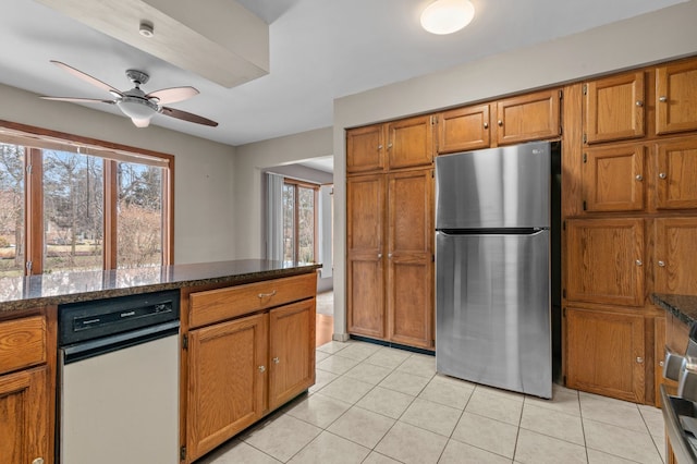 kitchen with light tile patterned floors, plenty of natural light, brown cabinets, and freestanding refrigerator