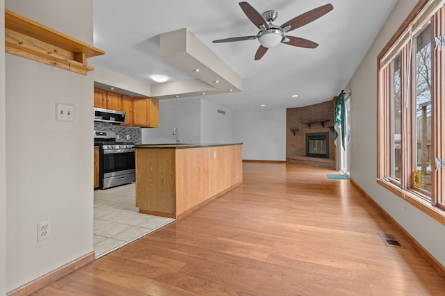 kitchen with light wood finished floors, visible vents, open floor plan, stainless steel appliances, and backsplash