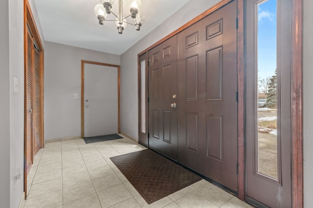 entrance foyer with light tile patterned floors, baseboards, and a notable chandelier