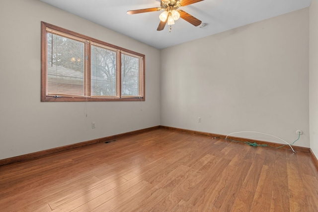 spare room featuring baseboards, ceiling fan, visible vents, and light wood-style floors