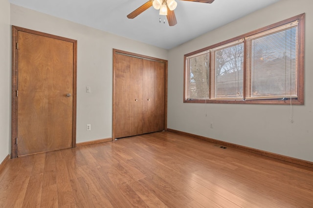 unfurnished bedroom featuring light wood finished floors, a closet, visible vents, a ceiling fan, and baseboards