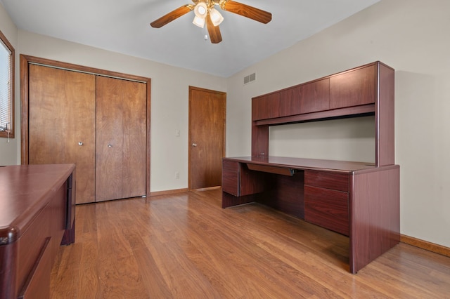 unfurnished office featuring visible vents, baseboards, a ceiling fan, built in study area, and light wood-style flooring