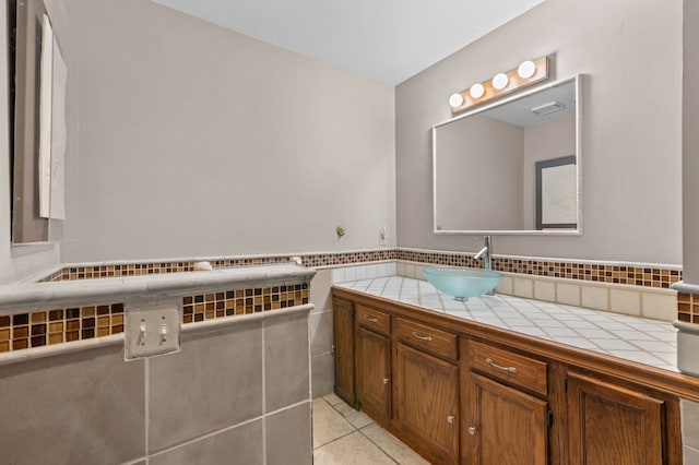 bathroom featuring visible vents, wainscoting, tile patterned floors, vanity, and tile walls