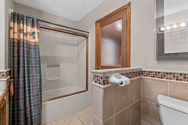 full bathroom with tile patterned flooring, toilet, tile walls, wainscoting, and shower / bath combination with curtain