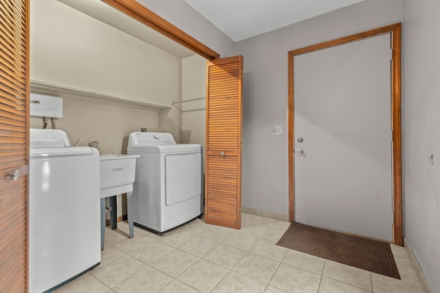 washroom featuring laundry area, washing machine and dryer, light tile patterned floors, and baseboards