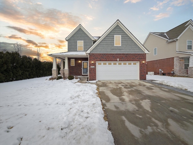 view of front of home featuring a garage, covered porch, brick siding, and driveway