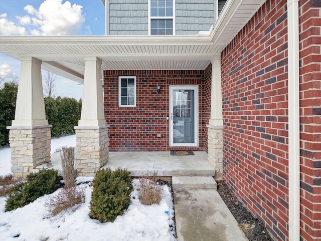 property entrance featuring covered porch and brick siding