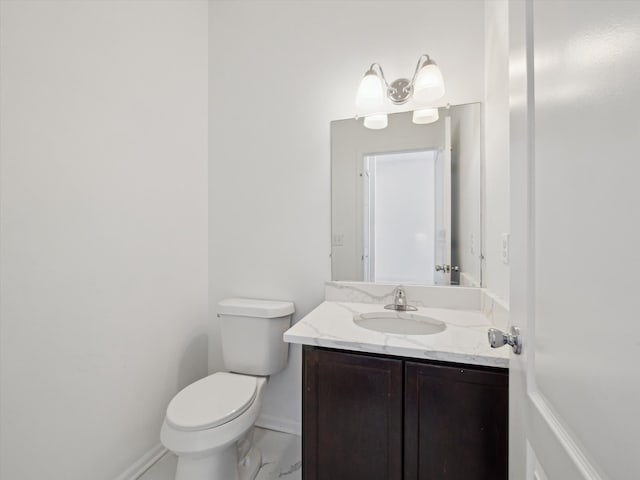 half bath with toilet, marble finish floor, baseboards, and vanity