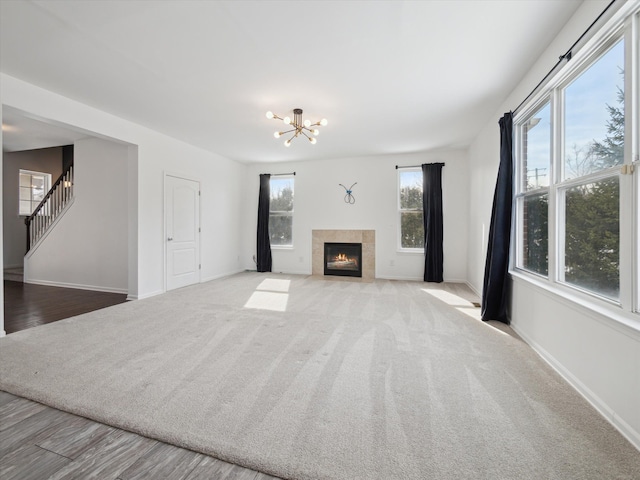 unfurnished living room featuring stairway, a tiled fireplace, and baseboards