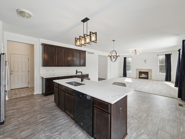 kitchen featuring black dishwasher, a fireplace, a sink, and dark brown cabinetry