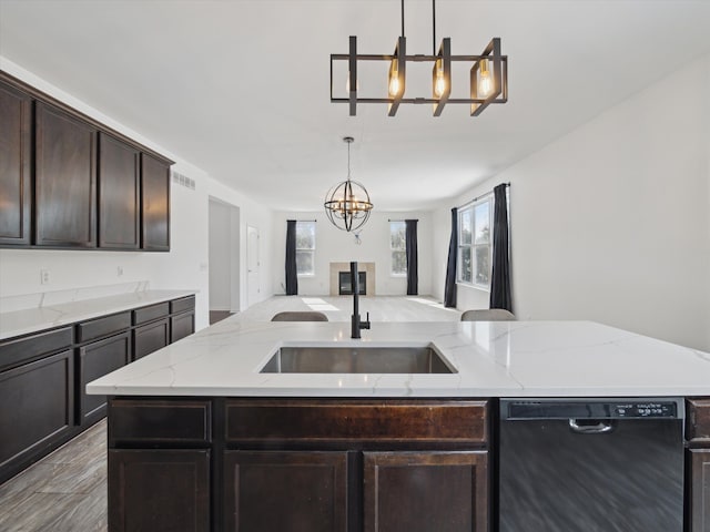 kitchen featuring pendant lighting, open floor plan, dark brown cabinetry, a sink, and dishwasher