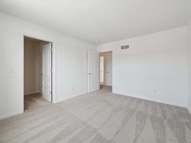 unfurnished bedroom with carpet, visible vents, a walk in closet, and baseboards