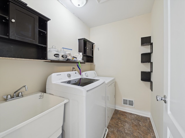 clothes washing area featuring a sink, visible vents, baseboards, washer and dryer, and cabinet space