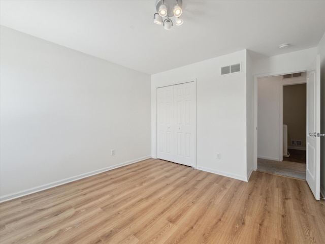 unfurnished bedroom with light wood finished floors, a closet, visible vents, and baseboards