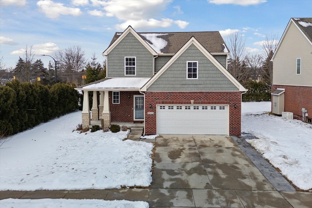 craftsman house with covered porch, brick siding, driveway, and an attached garage