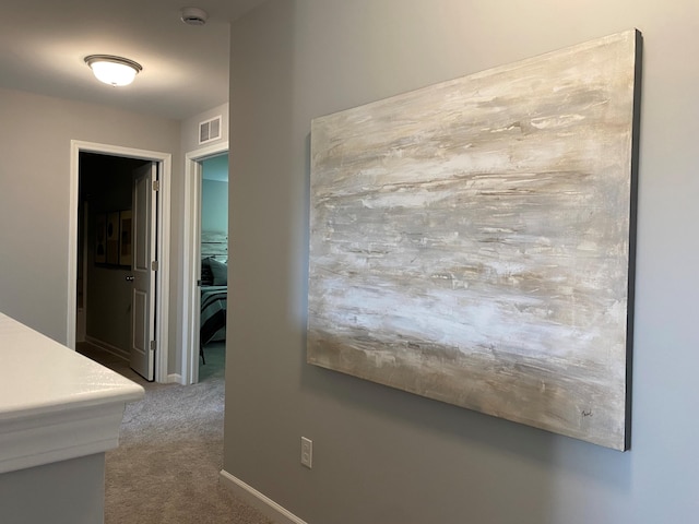 corridor with carpet floors, baseboards, and visible vents