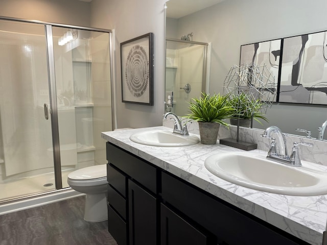 bathroom featuring wood finished floors, a stall shower, a sink, and toilet