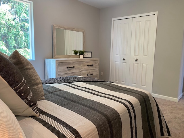 carpeted bedroom featuring baseboards and a closet