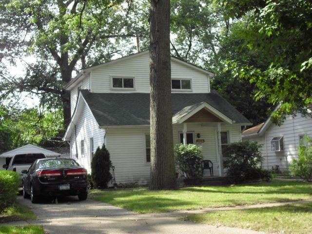 view of front of house with a front lawn and roof with shingles