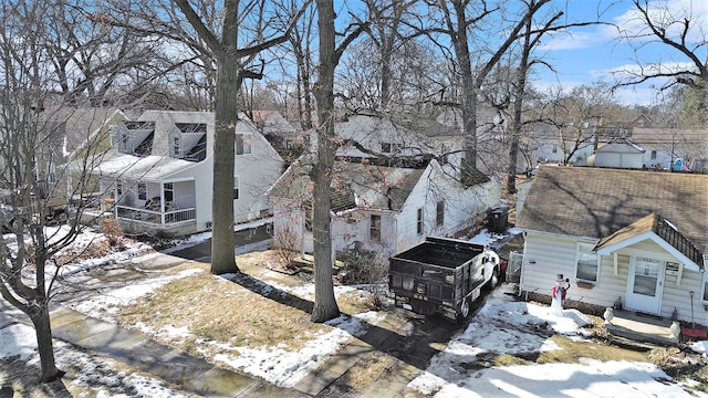 snow covered property with roof with shingles and a residential view