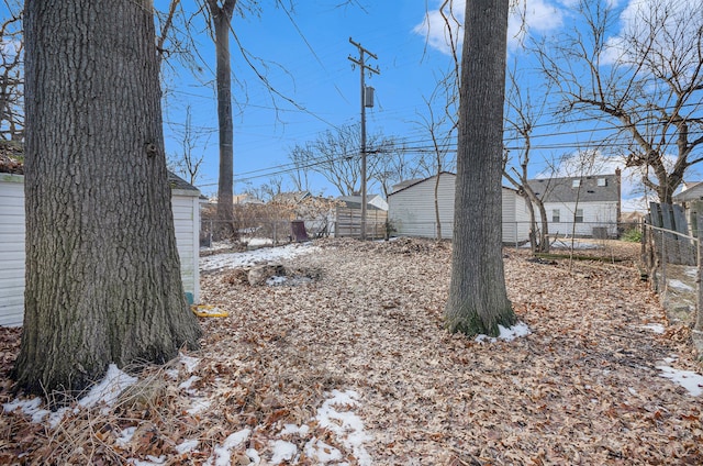 yard covered in snow featuring an outdoor structure and fence