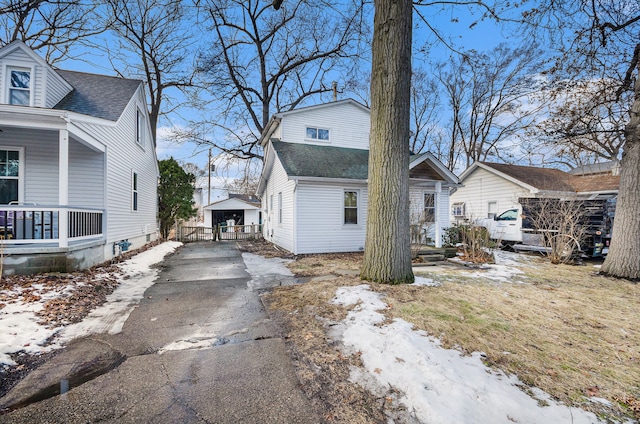 view of snow covered exterior featuring driveway and a shingled roof