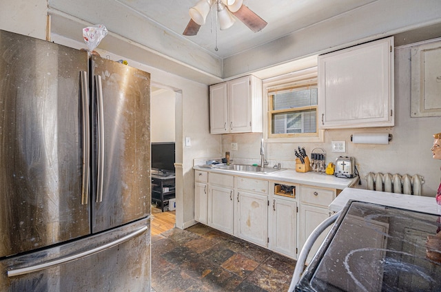 kitchen featuring light countertops, freestanding refrigerator, white cabinetry, and a sink