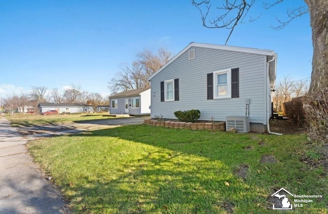 view of side of home with cooling unit and a lawn