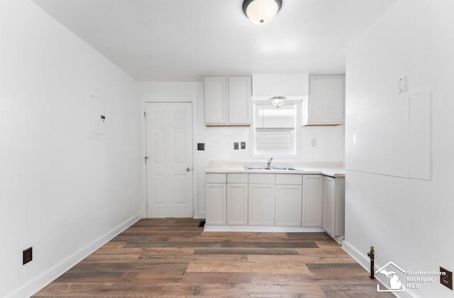 kitchen with dark wood-type flooring, baseboards, light countertops, and a sink